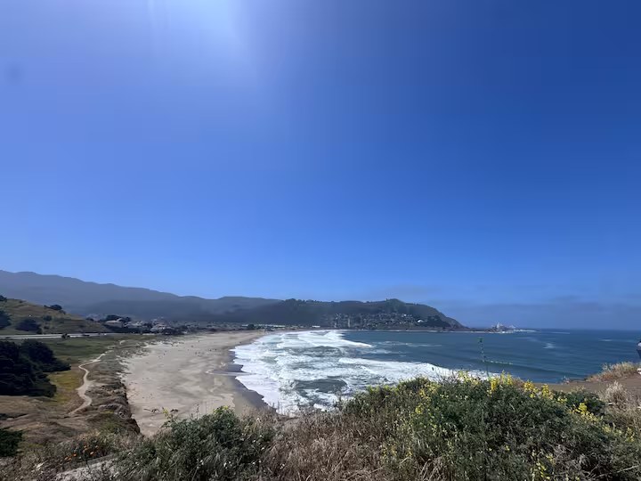 Panoramic view of Linda Mar Beach with mountains behind and surf rolling in