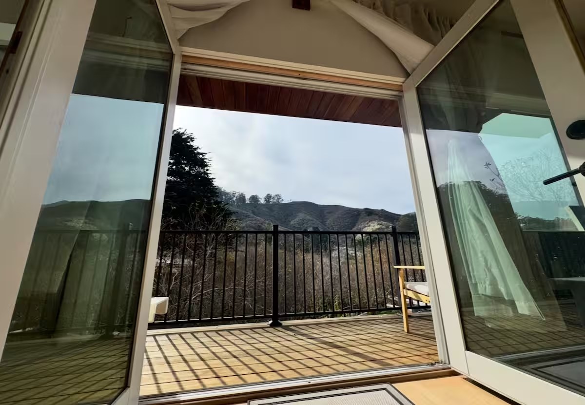 French doors from the bedroom opening onto a private balcony with a view of Montara Mountain