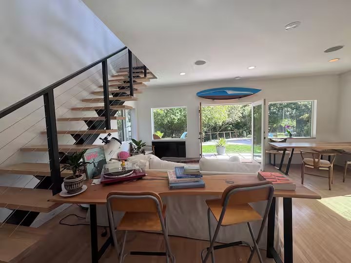 Open living and dining space with a floating wood-tread staircase and doors to the backyard